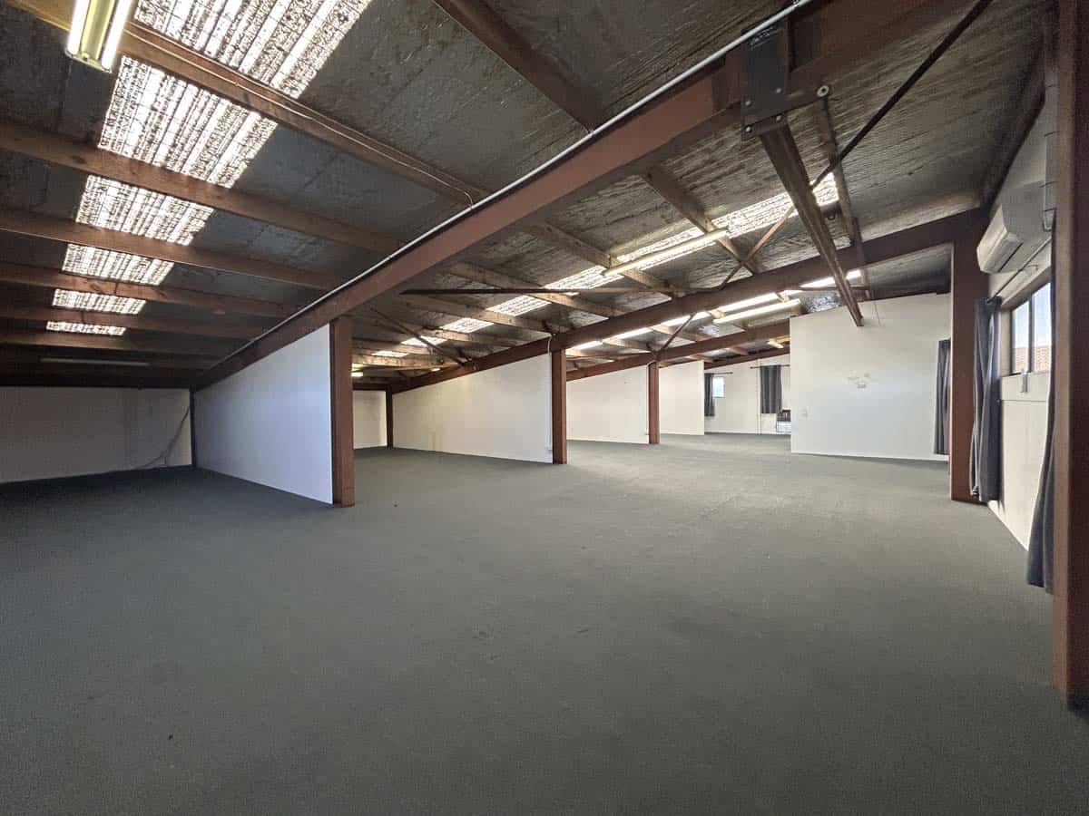 Spacious industrial warehouse interior with high ceilings and exposed roof structure.