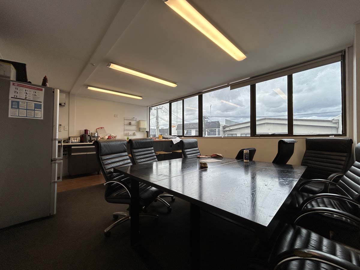 Modern office meeting room with large windows and black chairs.