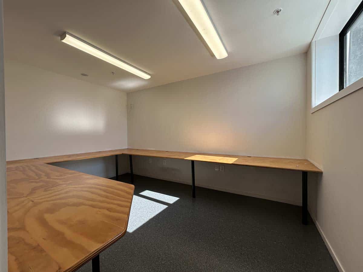 Modern office room with large window and wooden desk for work or meetings.