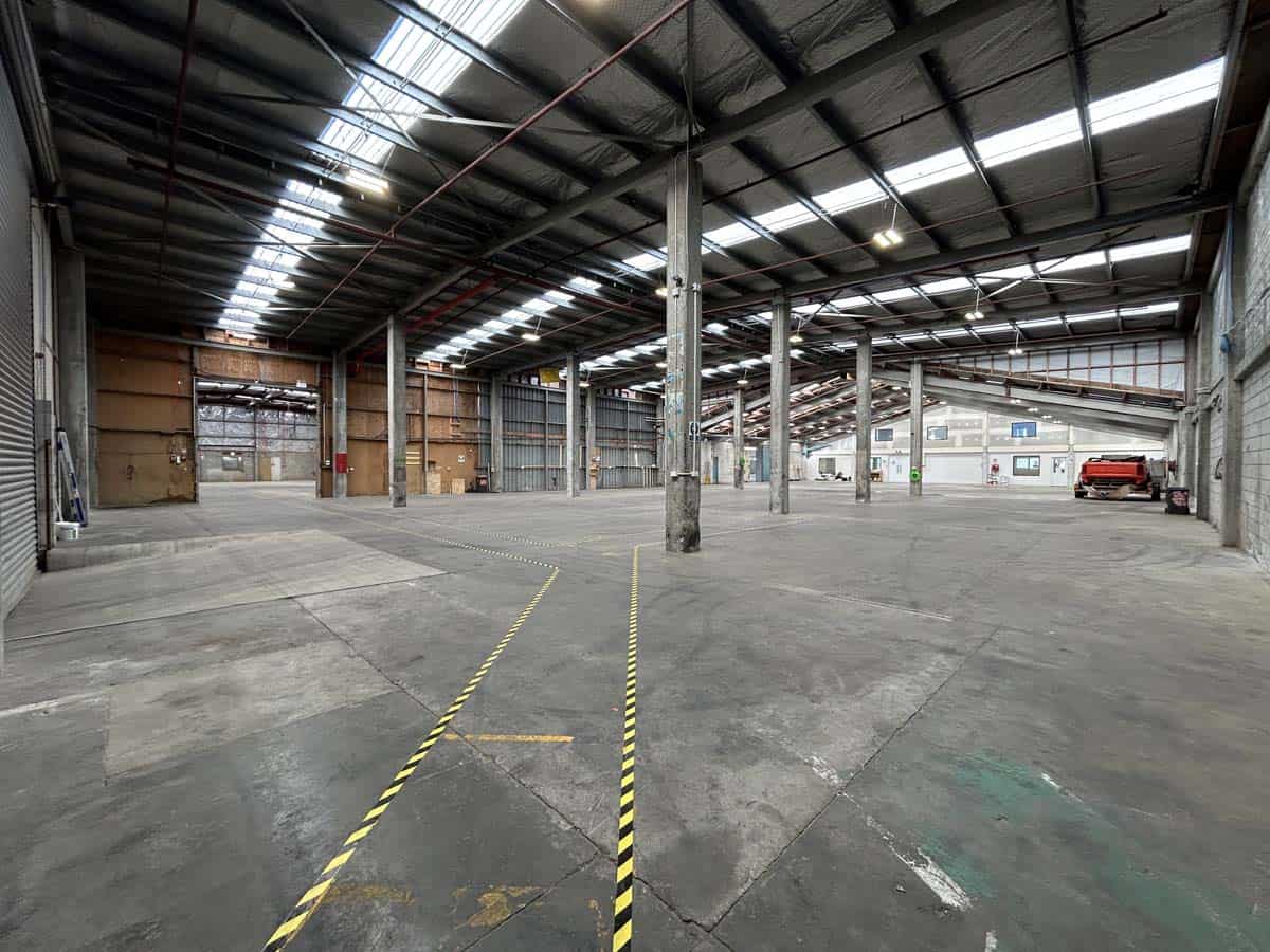 Empty industrial warehouse space with high ceilings and steel beams.