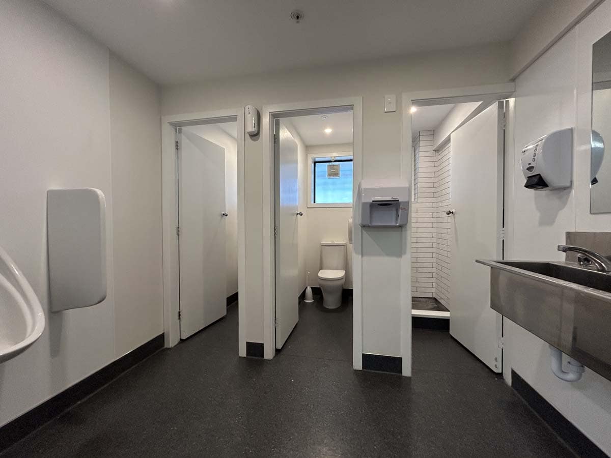 Accessible public bathroom with toilet, sink, and hand dryer in a commercial space.