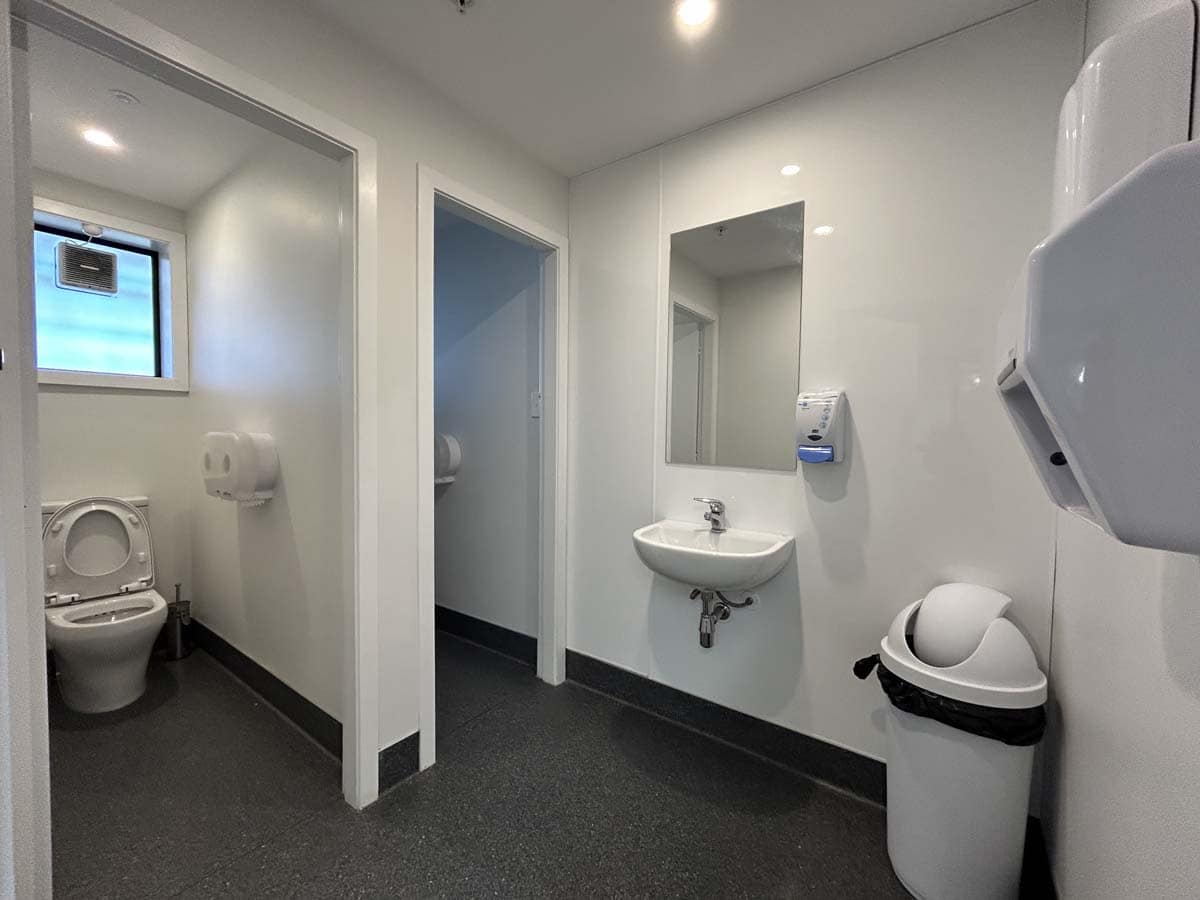 Public restroom with clean, white interior, sinks, and toilet facilities.