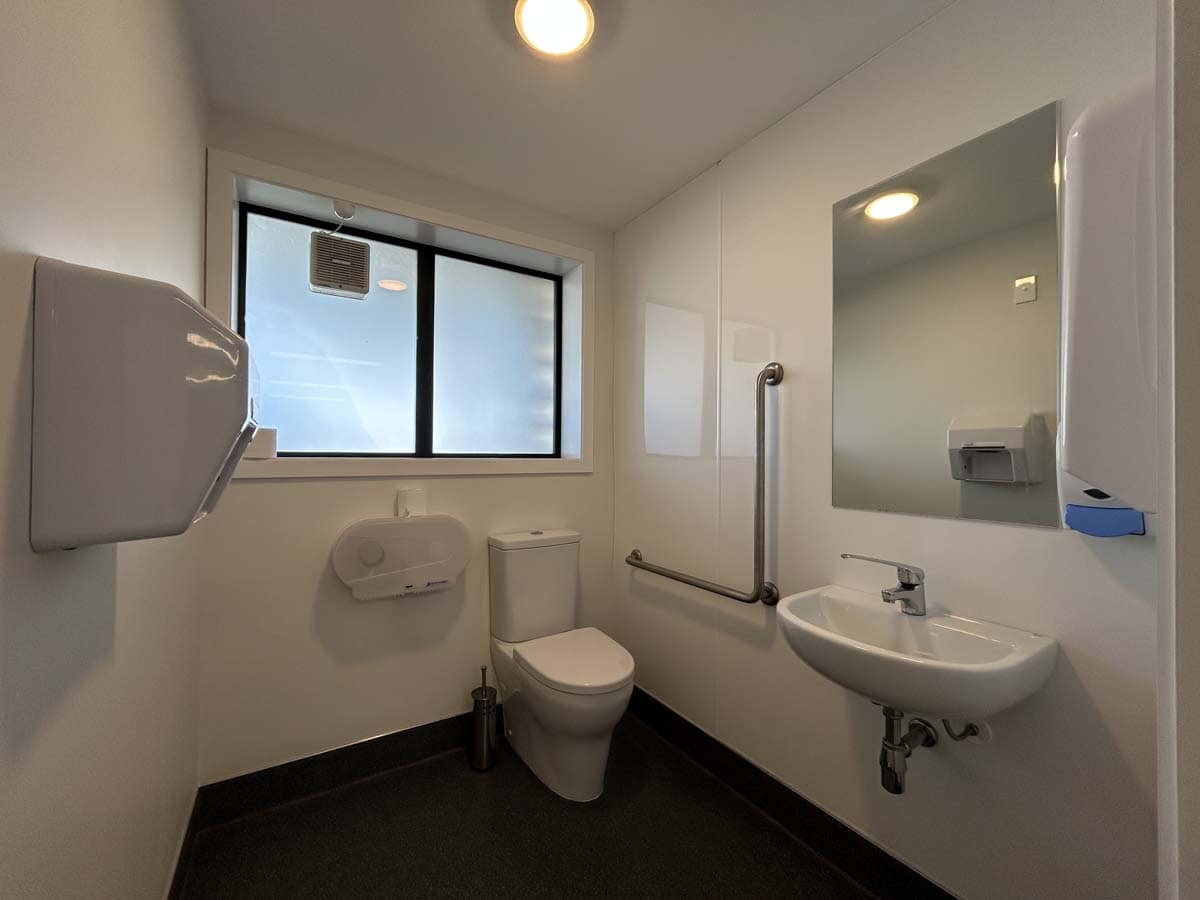Accessible bathroom with toilet, sink, and grab bars at 69 Waione Street.