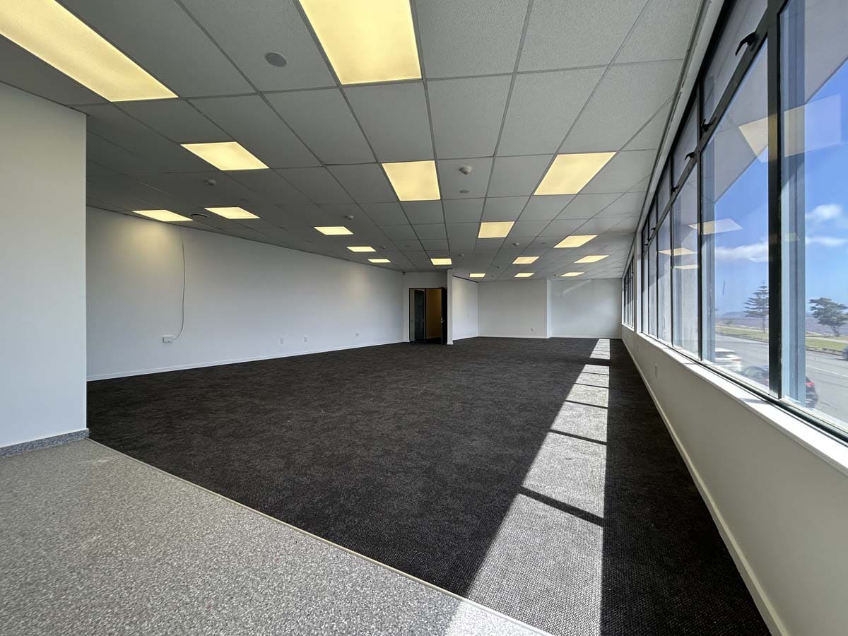 Spacious office interior with natural light and contemporary ceiling lights.