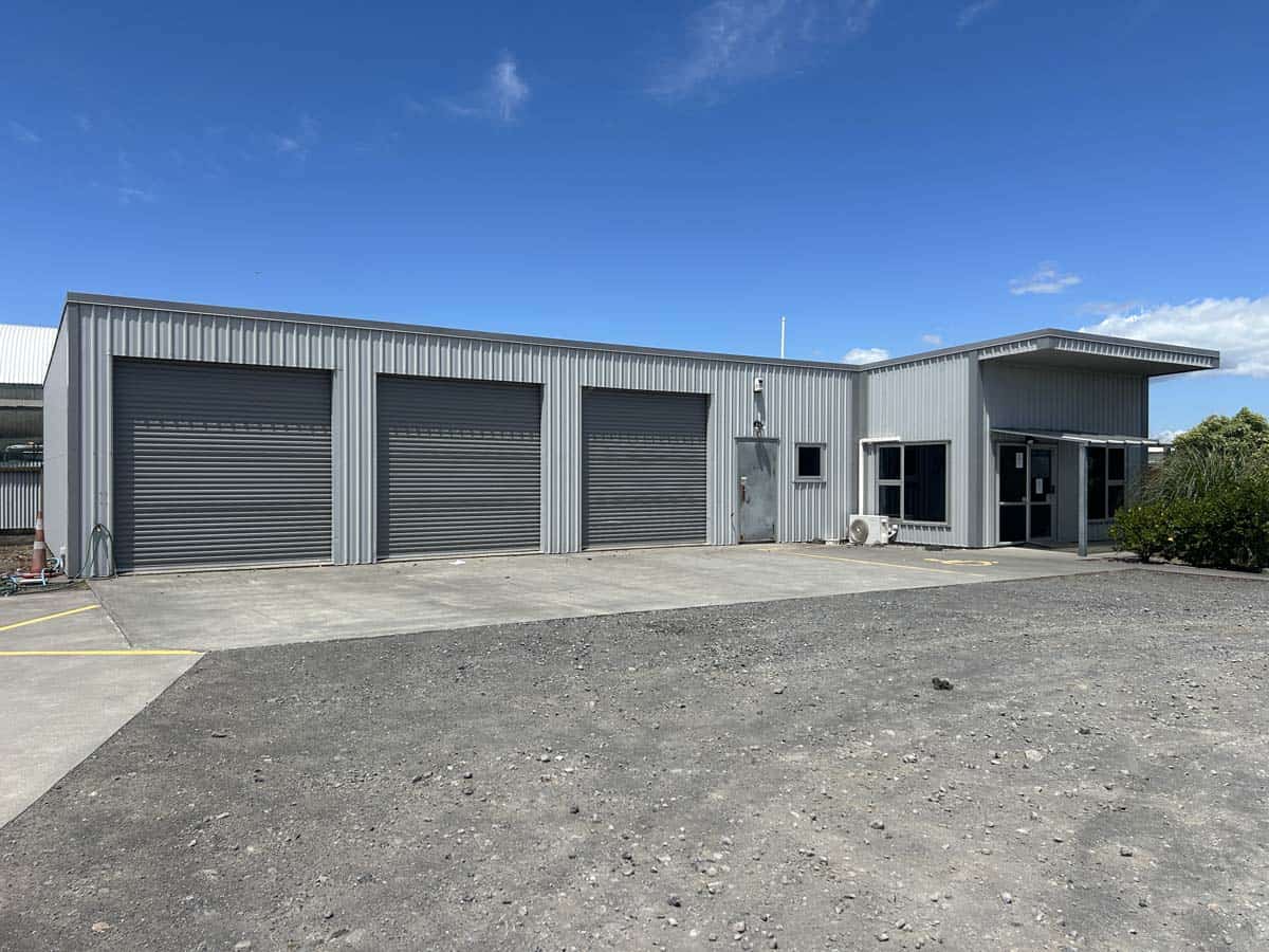 Modern industrial warehouse with multiple roller doors at 76 De Havilland Drive.