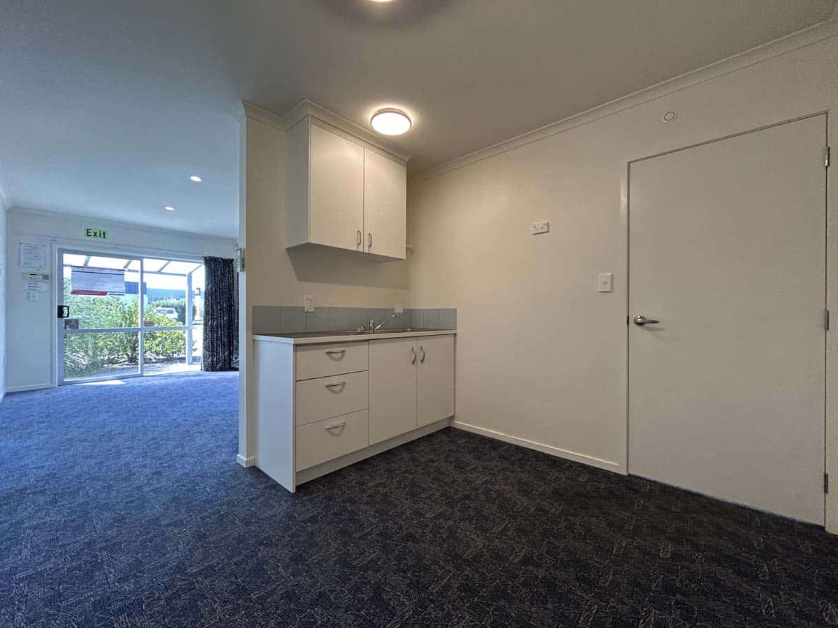Bright and clean kitchen space with white cabinetry and grey countertops.