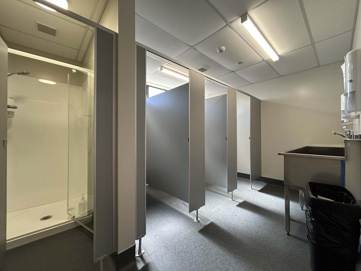 Clean and accessible commercial restroom with shower and privacy cubicles.