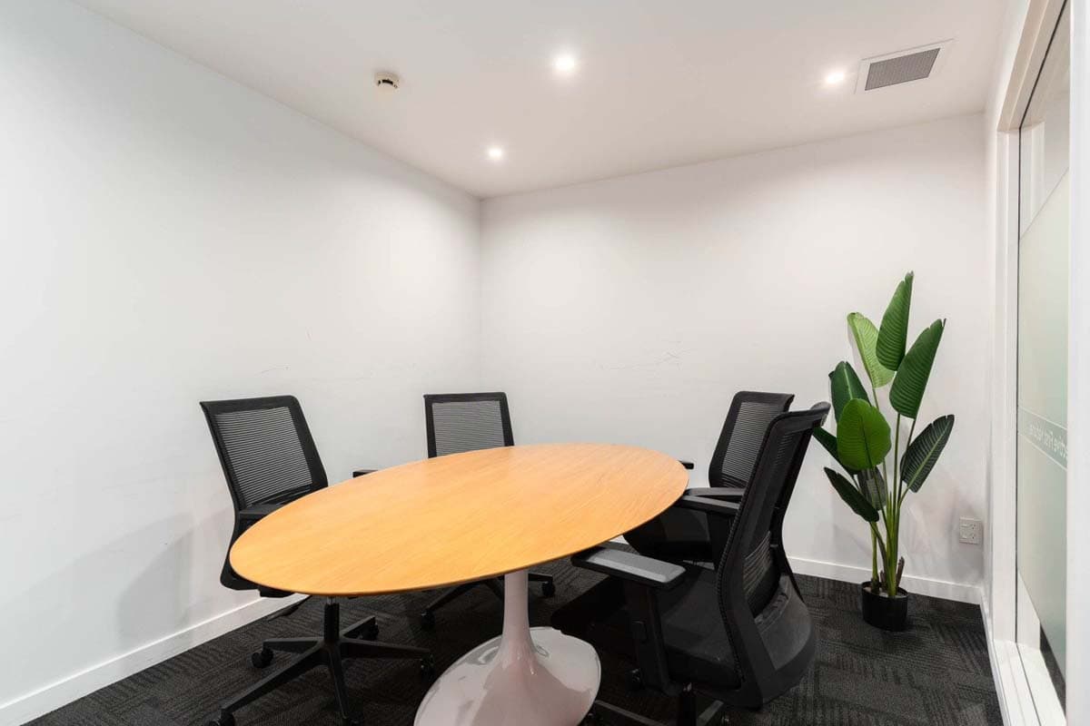 Modern office meeting room with a wooden table and black chairs.