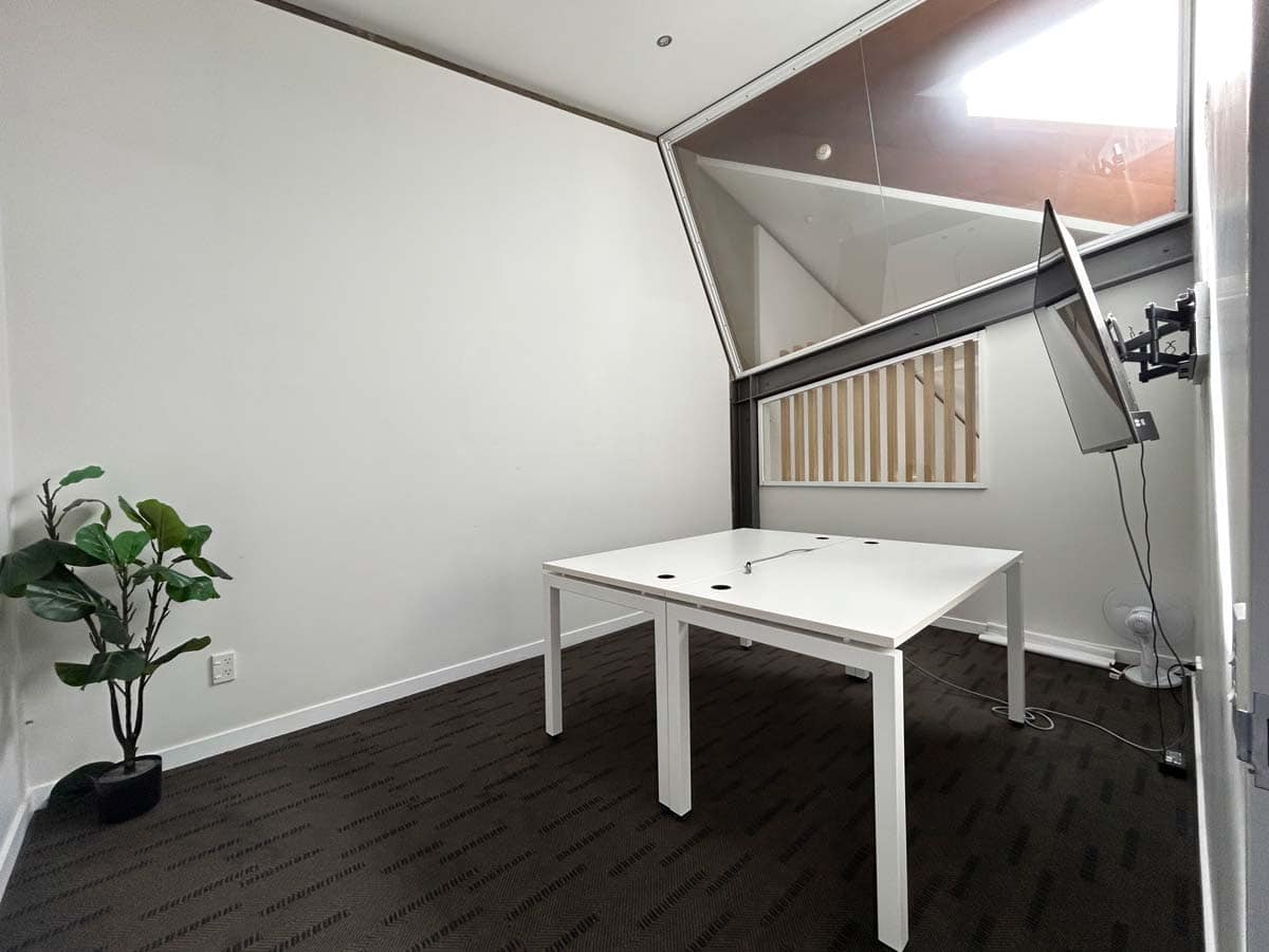 Modern office with white walls, a white desk, and a large window with natural light.