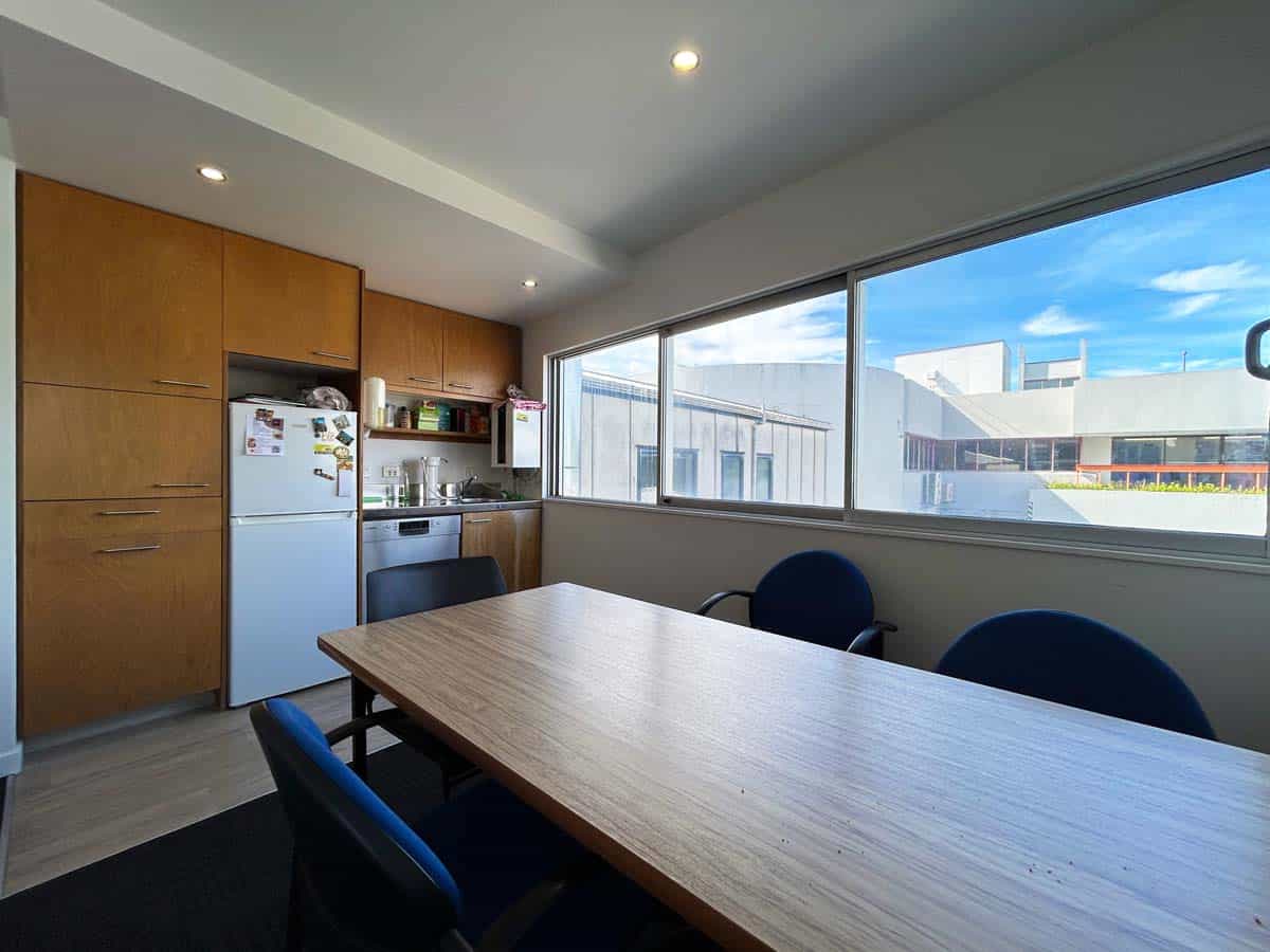 Image of a contemporary office meeting room with a wooden table, chairs, and large window overlookin.