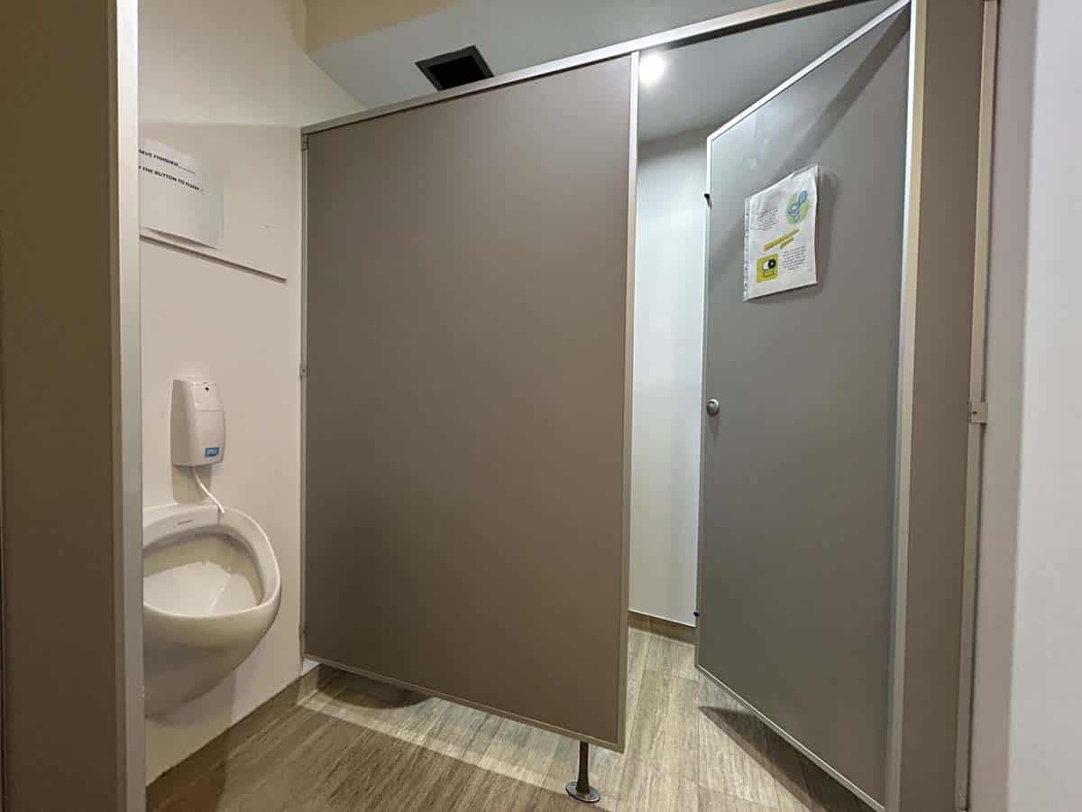 Accessible public restroom with privacy partitions and hand sanitizer.