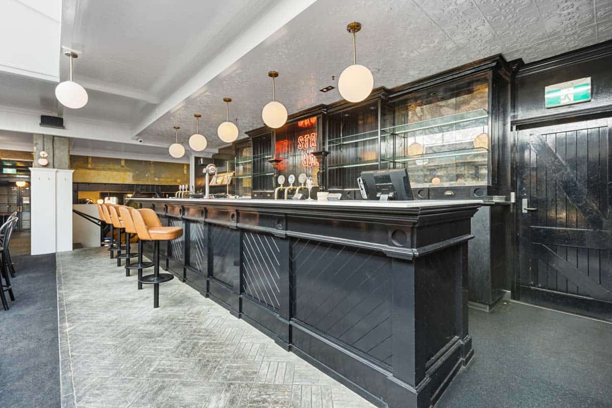 Modern bar interior at White Lion with black wood finishes and seating.