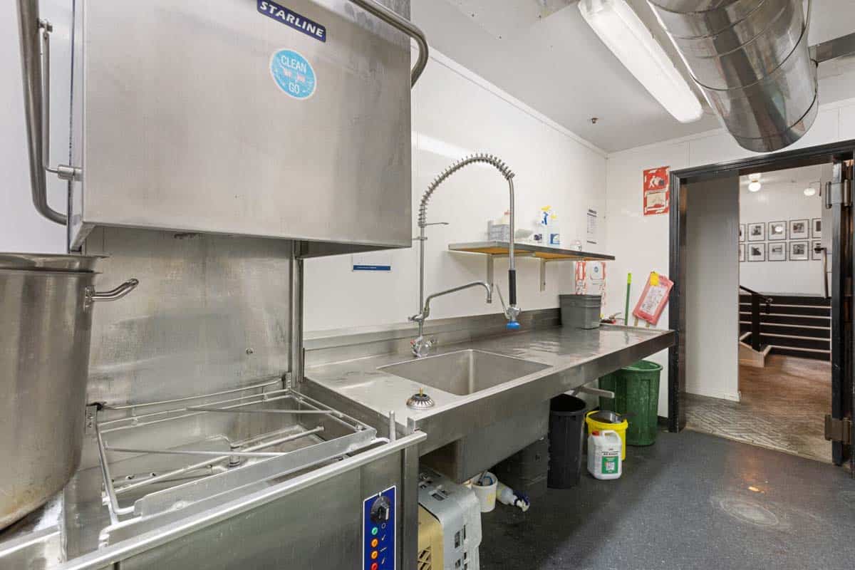 Commercial kitchen with stainless steel sink, cleaning station, and storage at 31 Gover Street.
