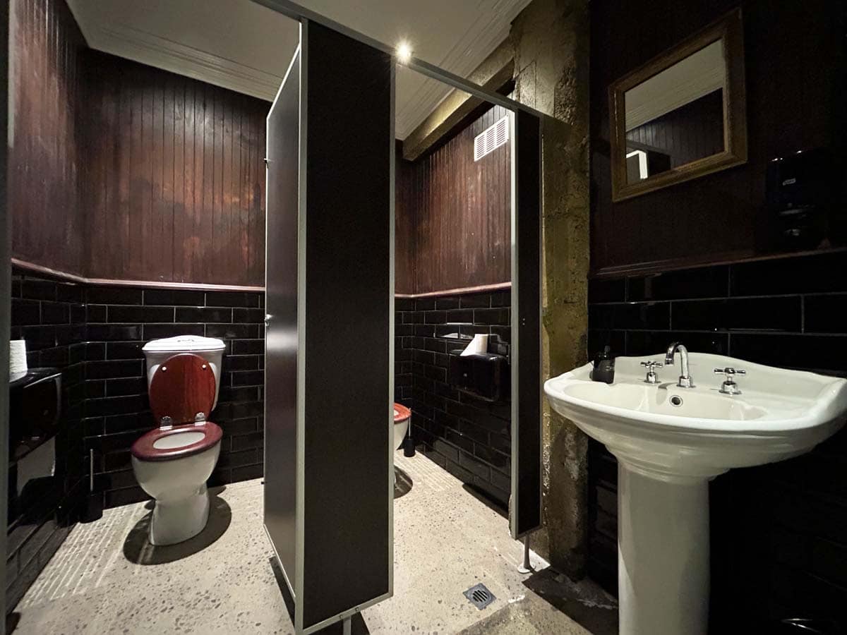 Modern bathroom with black tiles, white sink, and toilet at 31 Gover Street.