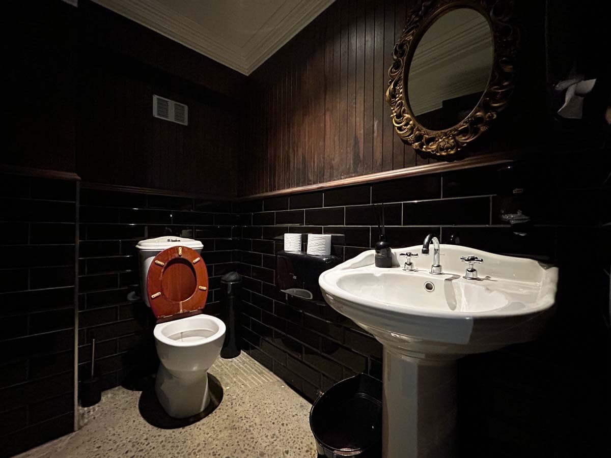 Stylish bathroom featuring a white toilet and sink with dark wood and tile accents.
