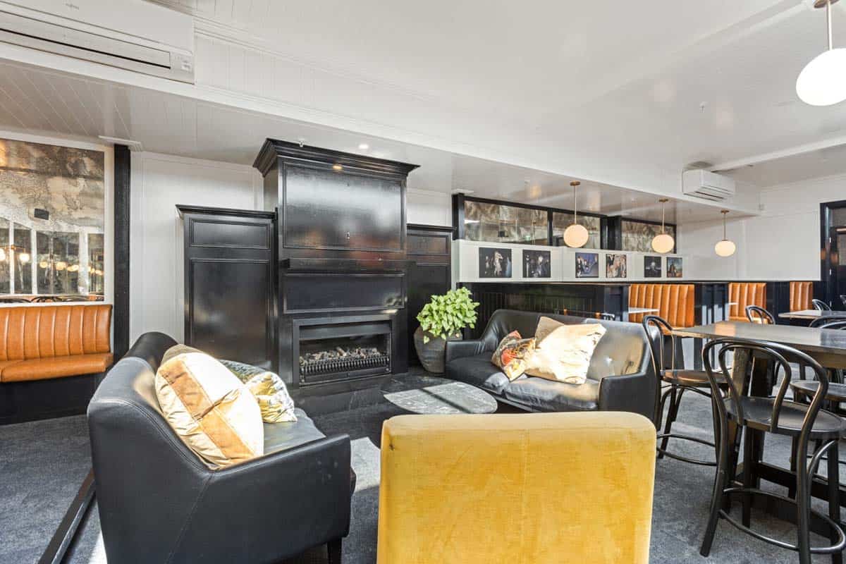 Modern lounge area at White Lion with black sofas, yellow armchair, and stylish decor.