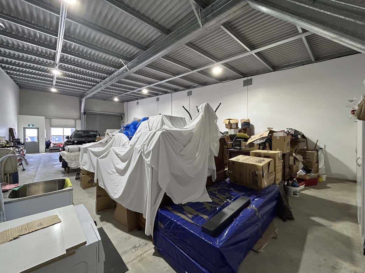 Storage unit filled with boxes, furniture, and covered items at White Lion, Unit 4, 7 Hudson Road.