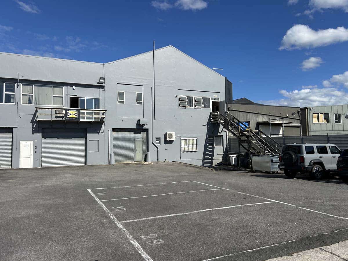Commercial building at 100 Gill Street with parking lot and blue sky.