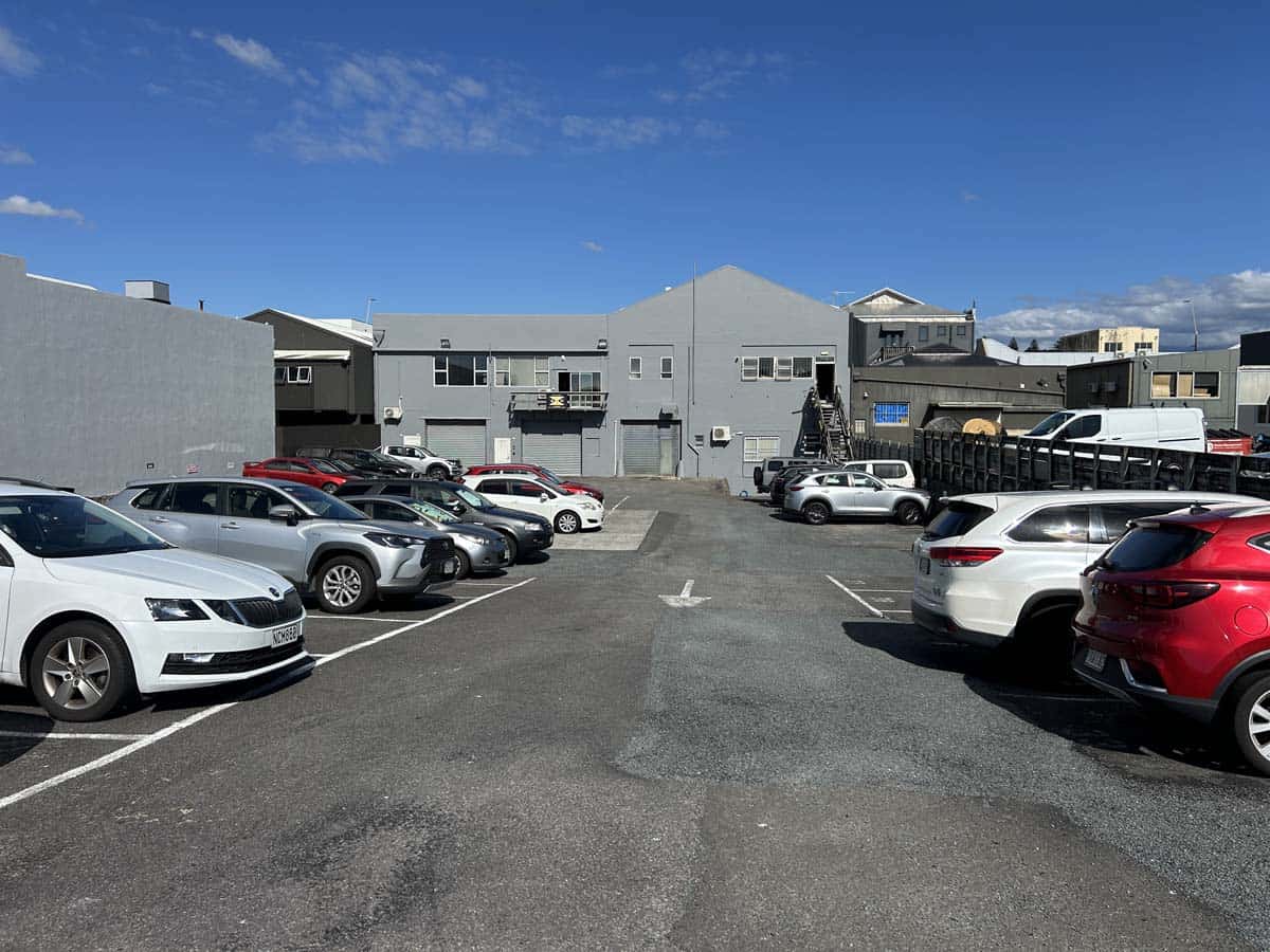 Parking lot with multiple cars in front of White Lion building at 100 Gill Street.