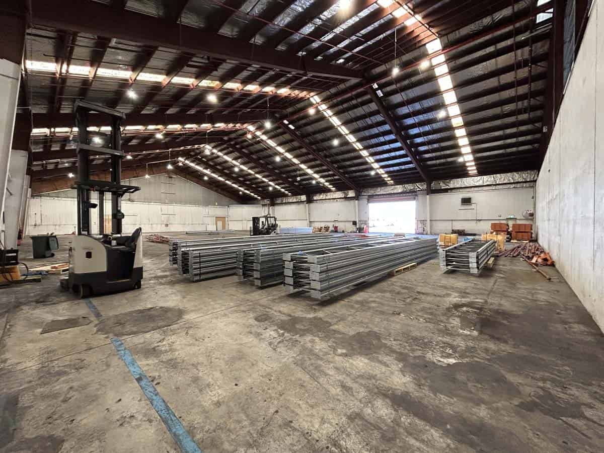 Interior view of White Lion warehouse with stacked metal beams and forklift.