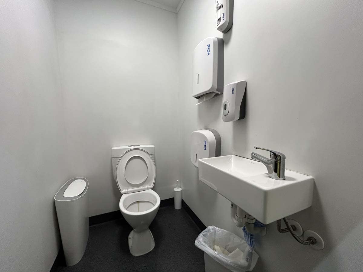 Clean and modern restroom with toilet, sink, and hygiene products.