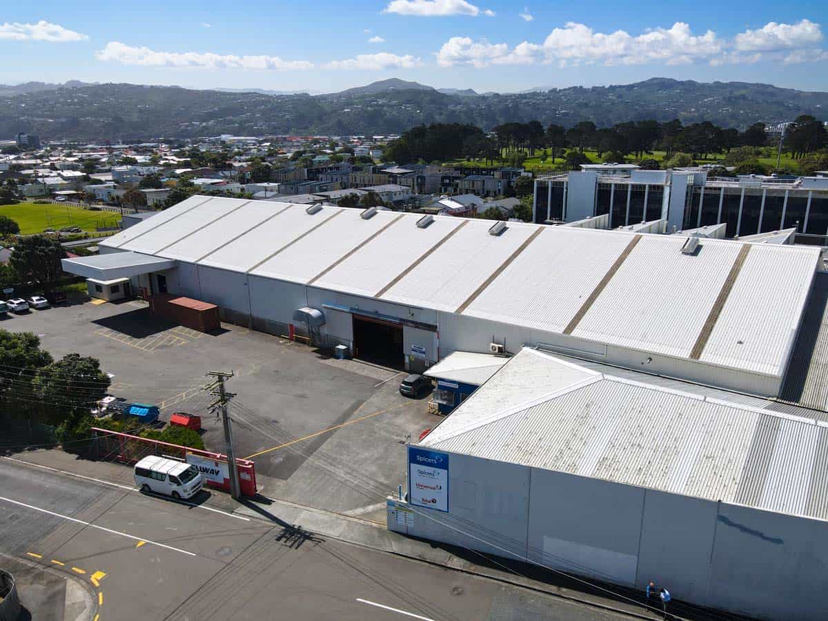 Large industrial warehouse building with white roof at 38 East Street, surrounded by parking and cit.