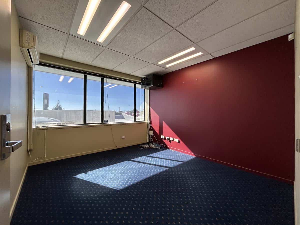 Bright office with large windows and red accent wall.