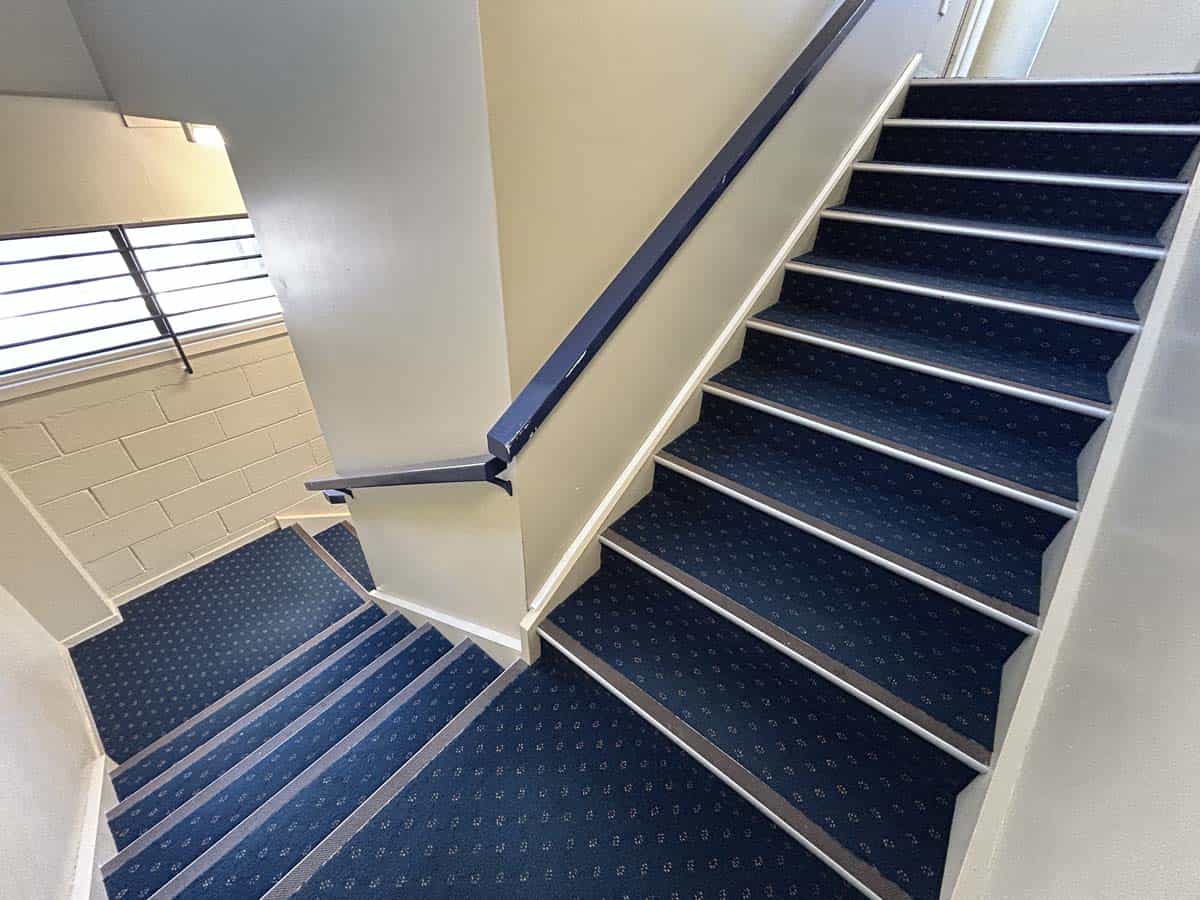 Staircase with blue carpet and white walls in a modern building.