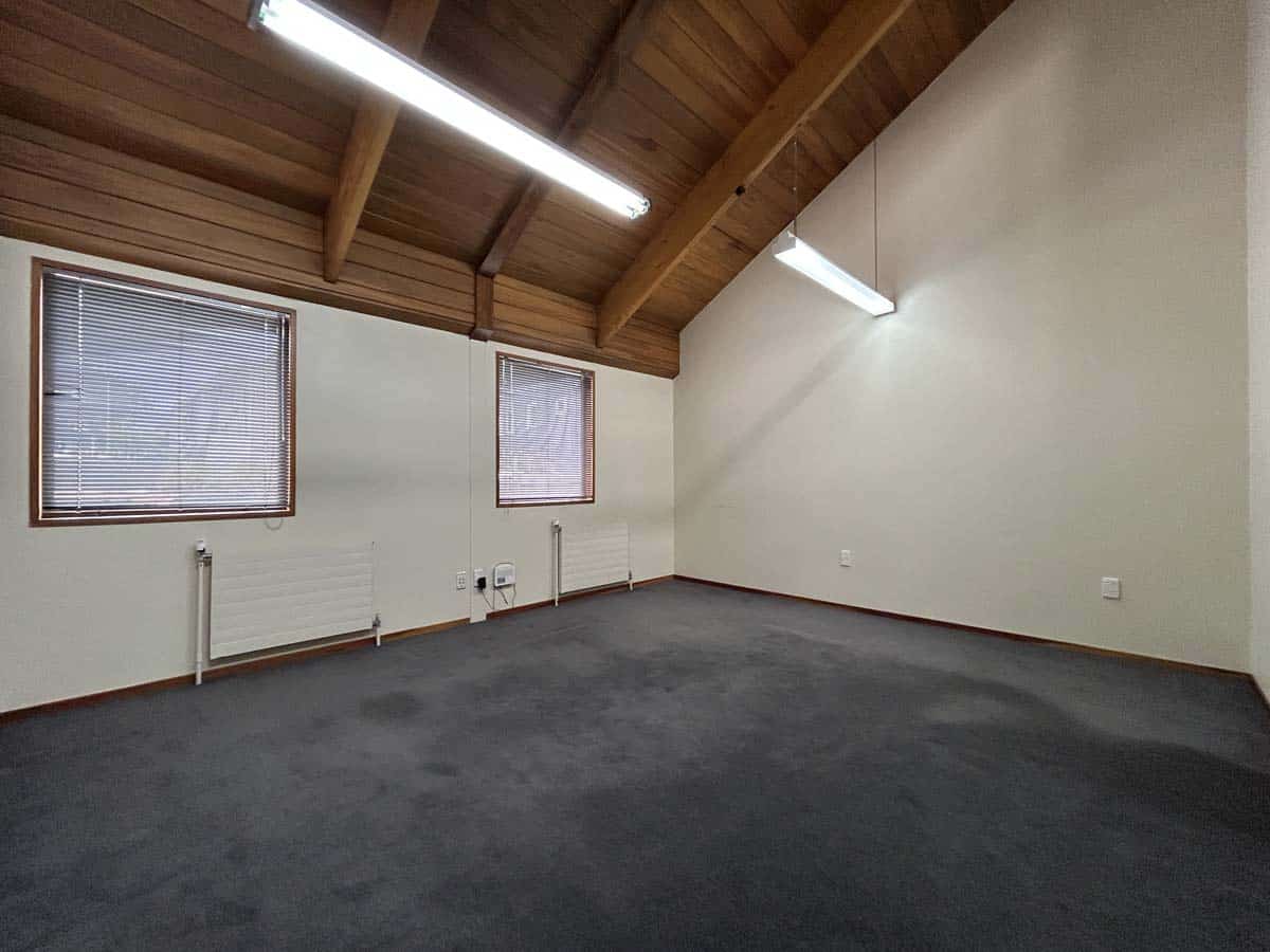 Interior view of a modern office room with wooden ceiling and large windows.