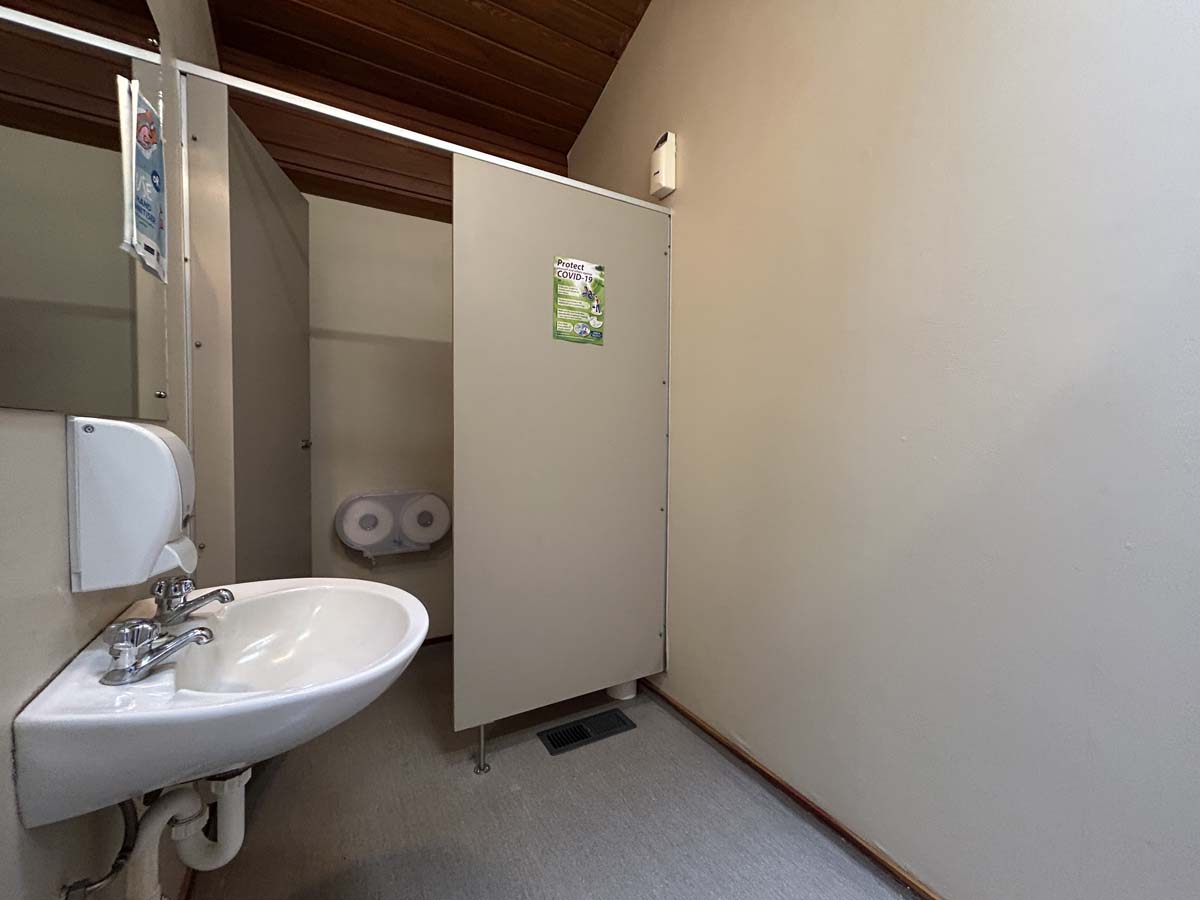 Public restroom with sink and toilet paper rolls in a commercial setting.