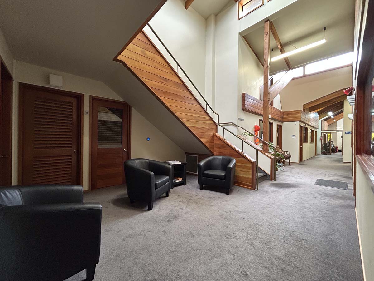 Modern lobby area with black chairs, wooden staircase, and natural light at Powderham Business Centr.