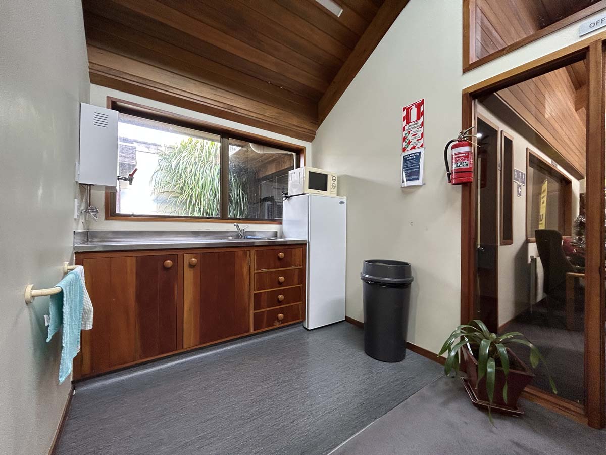 Interior view of a modern office kitchen at Powderham Business Centre, featuring wooden cabinetry an.