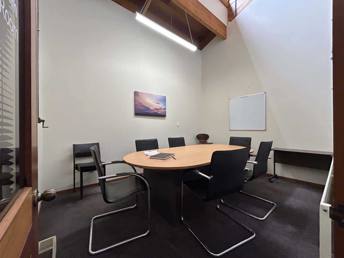 Modern meeting room with black chairs, wooden table, and whiteboard at Powderham Business Centre.