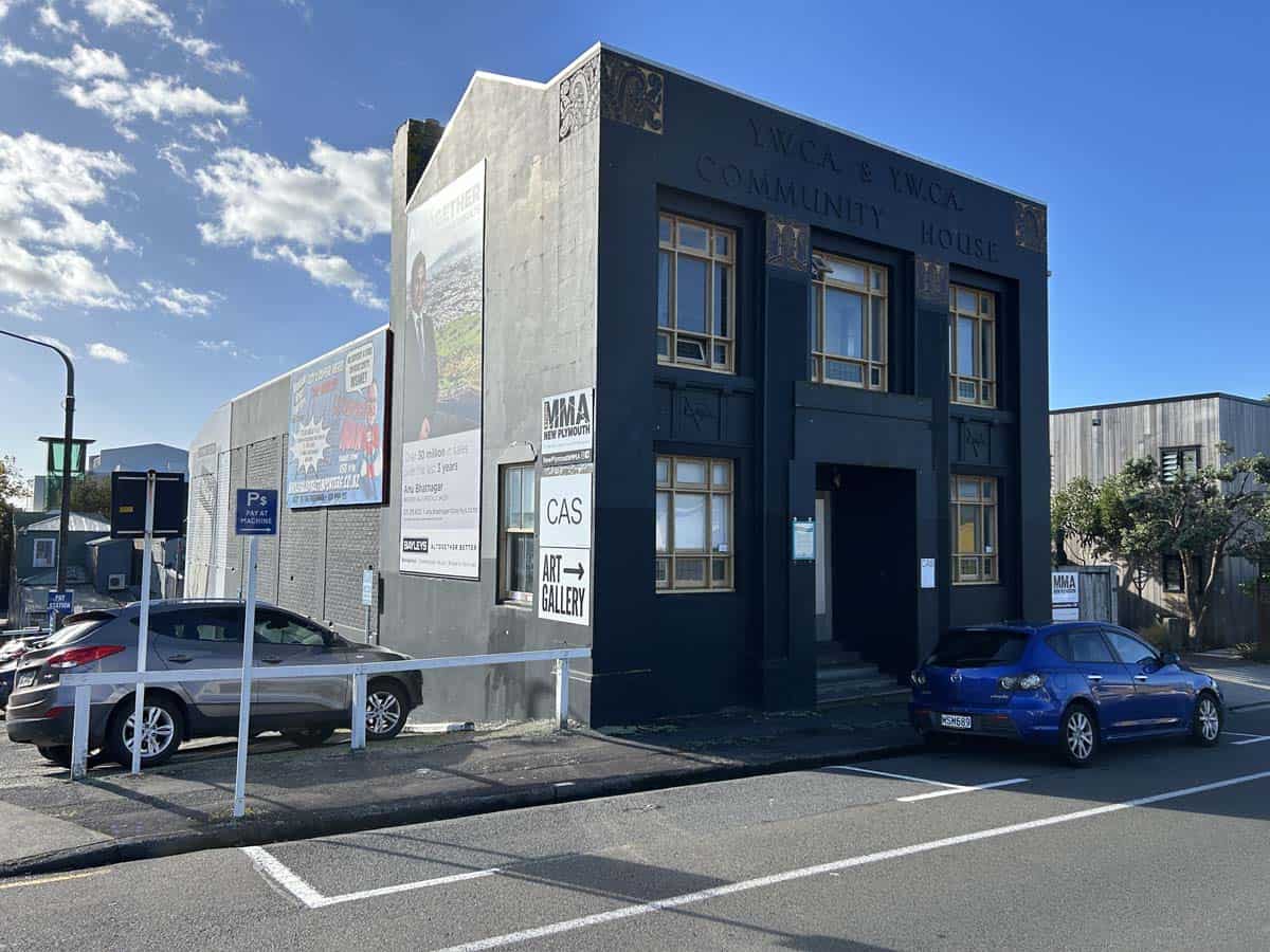 White Lion Community House at 74 Powderham Street, featuring a dark blue exterior and parking area.