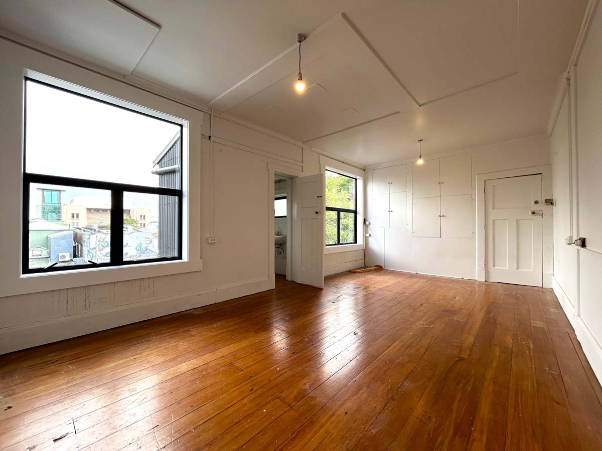 Bright, empty office room with large windows and wooden floors.