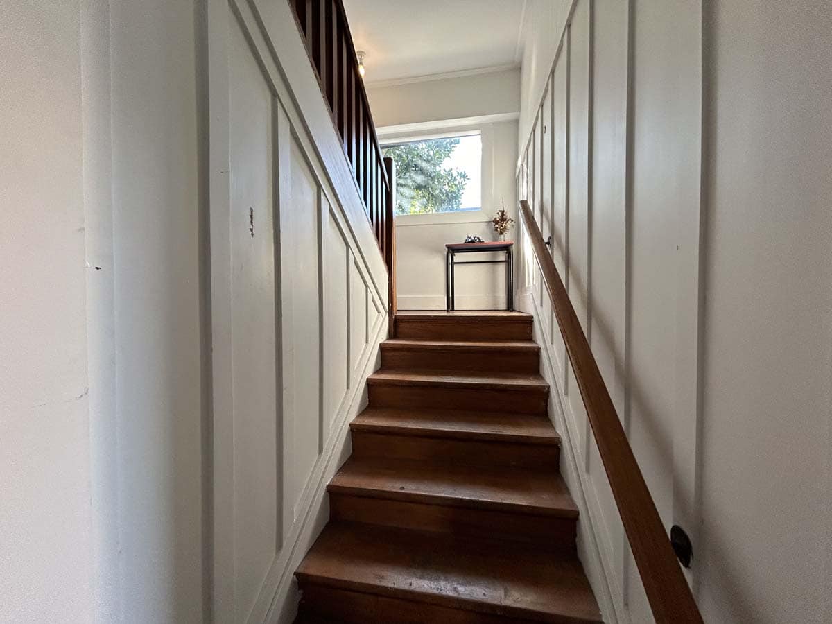 Interior staircase at 74 Powderham Street, featuring wooden steps and white paneling.