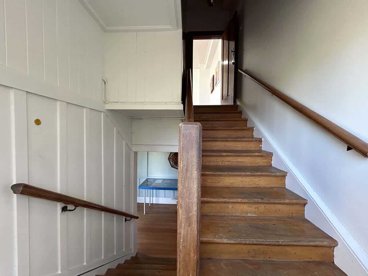 Staircase inside a historic building at 74 Powderham Street, featuring wooden steps and white paneli.