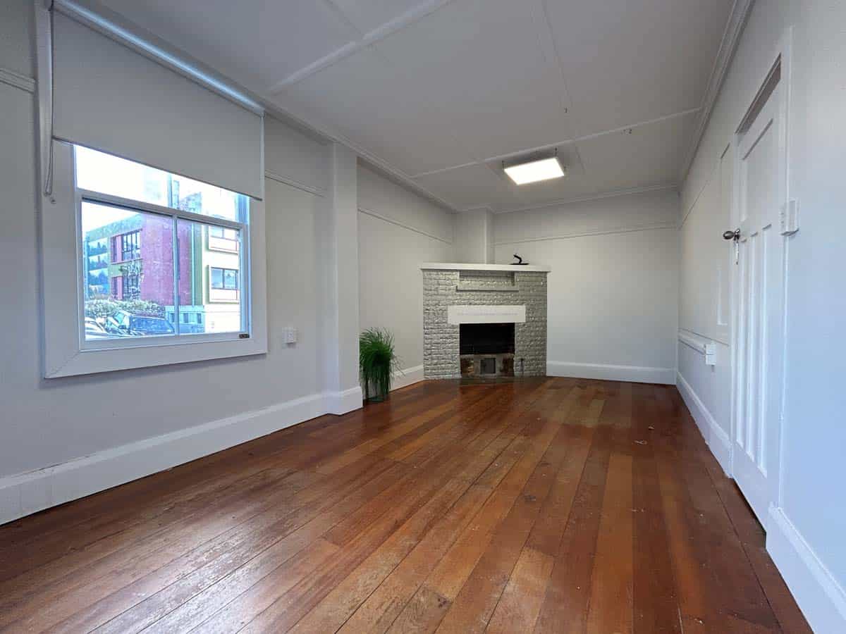 Spacious living room with wooden floors and fireplace at 74 Powderham Street.