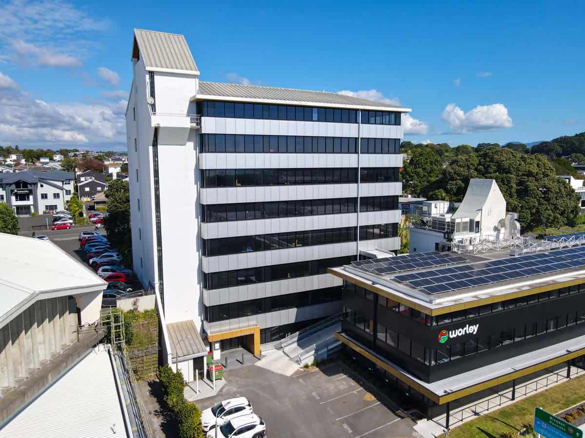 Modern office building with solar panels and surrounding parking.
