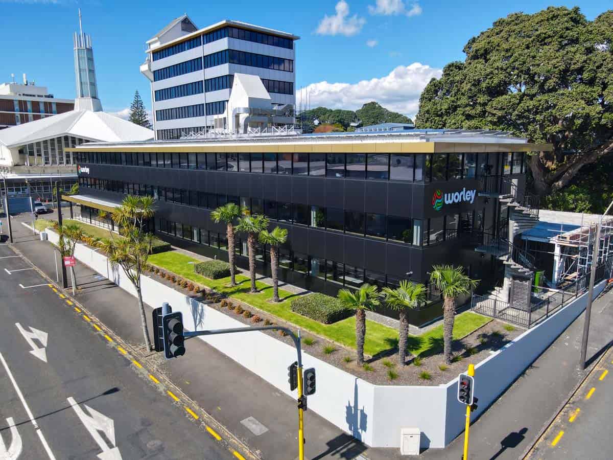 Modern commercial office building with black facade and palm trees in Auckland.
