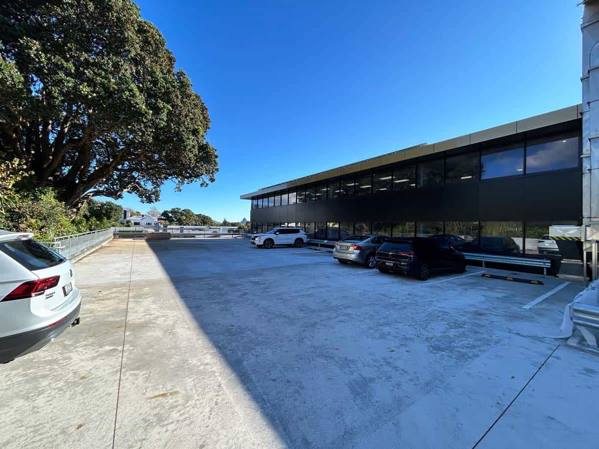Modern office building with glass facade and parking lot.