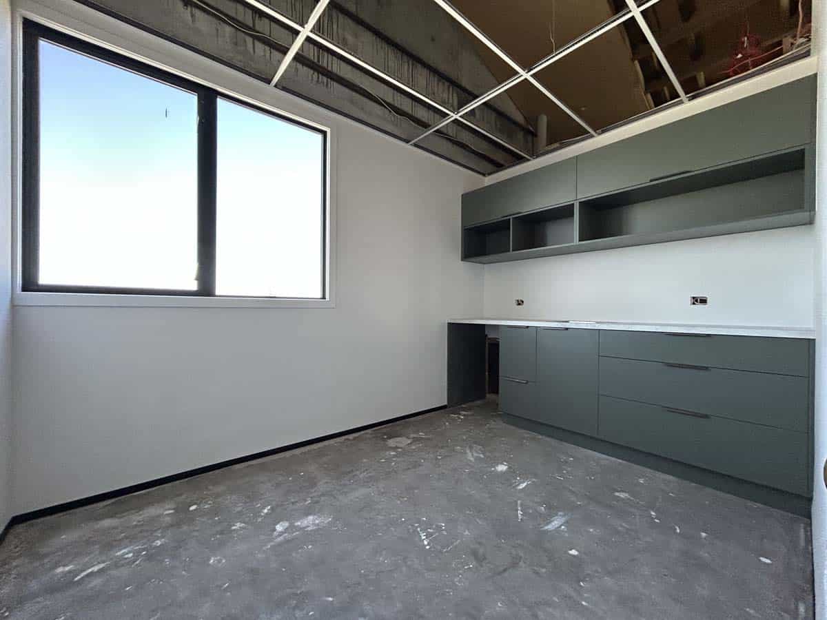 Modern kitchen with grey cabinets and large window.