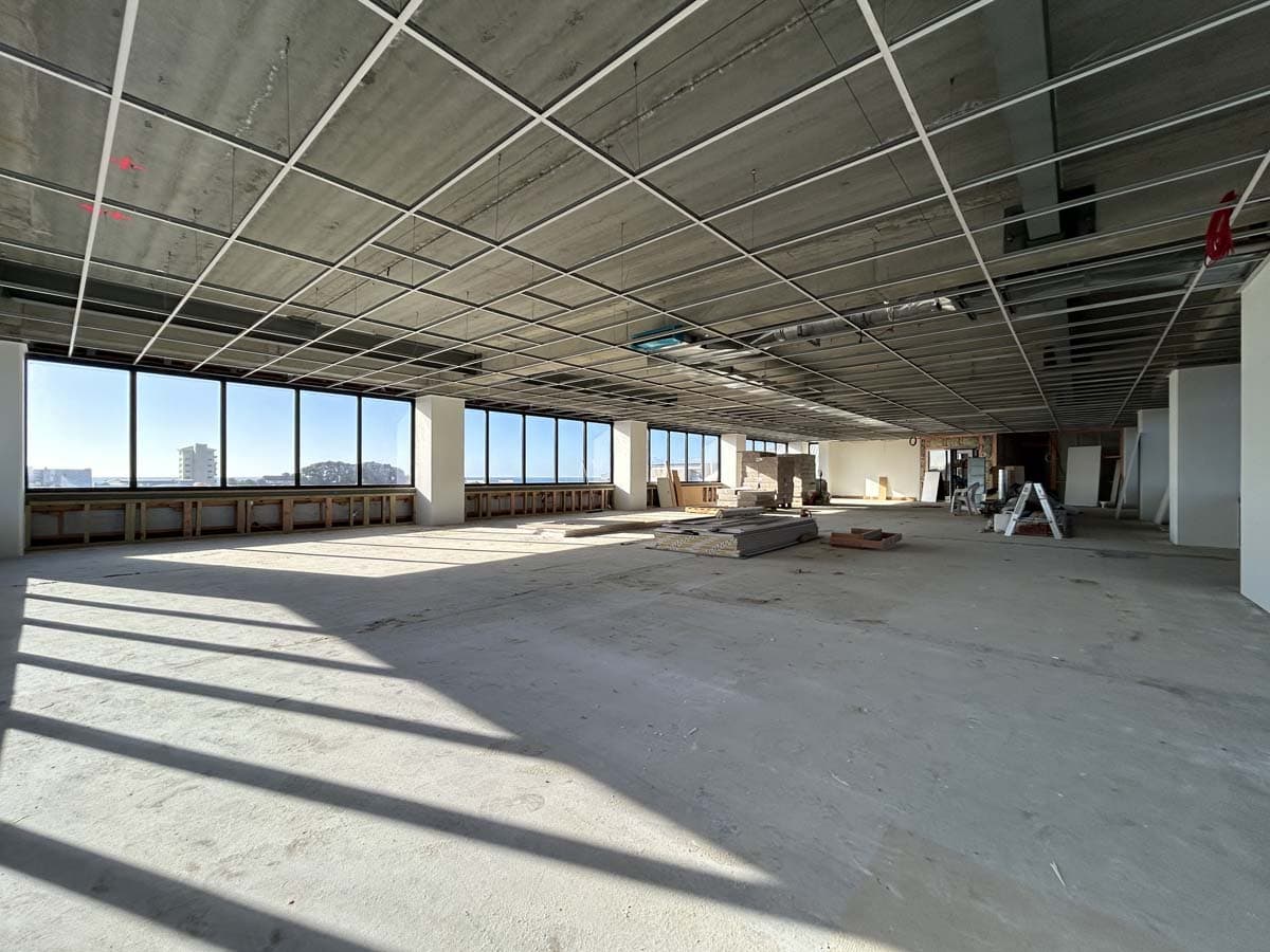 Spacious unfinished commercial building with large windows and natural light.