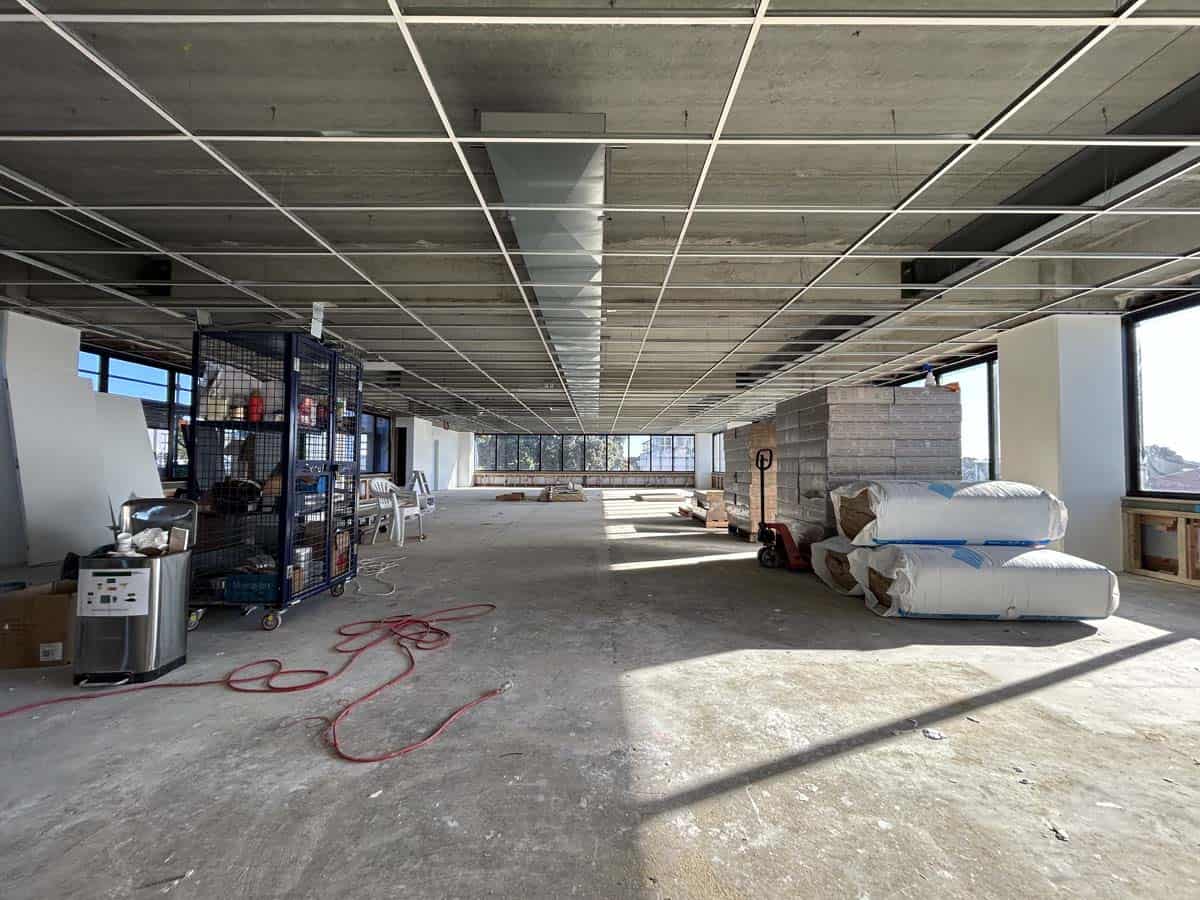 Interior view of an under-construction office space with ceiling panels and building materials.