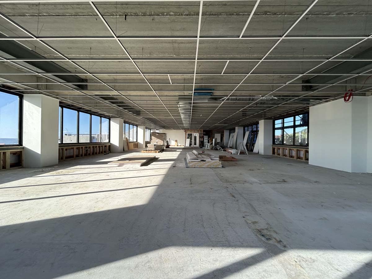 Modern office space under construction with large windows and open layout.