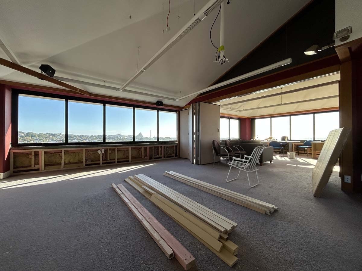 Modern office space with large windows and construction materials inside.