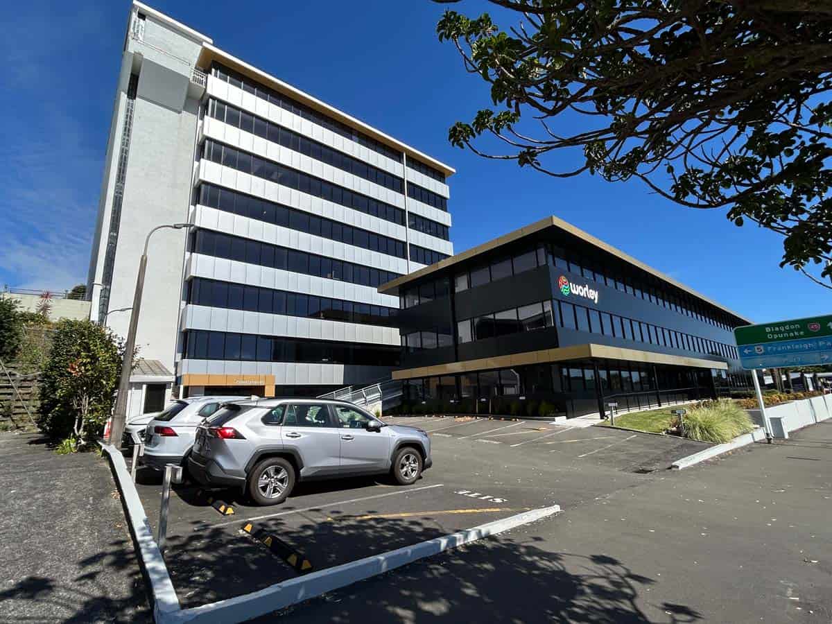 Modern office building with parking lot and clear blue sky.