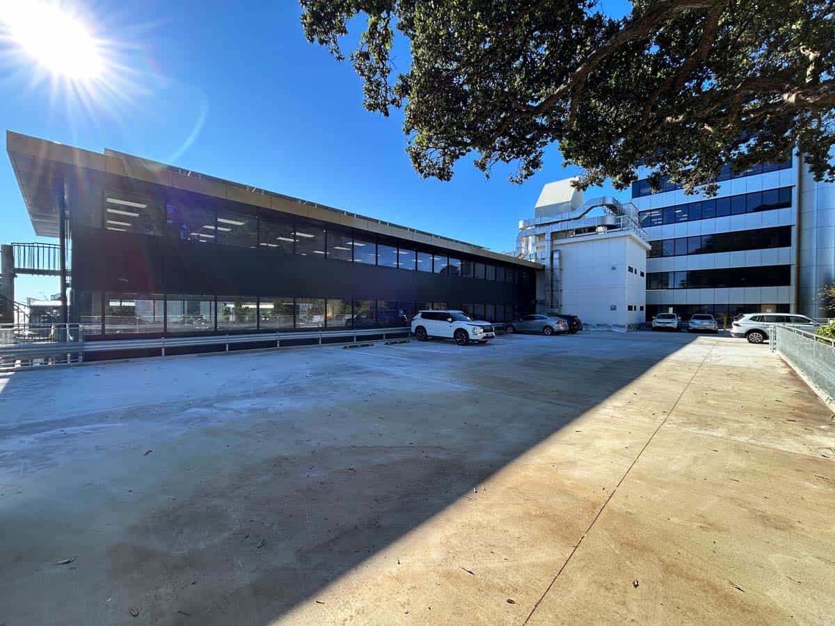 Modern office building with glass facade and parking area.