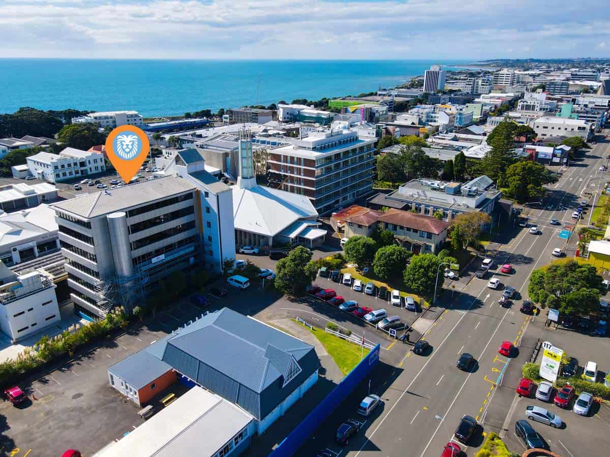 Aerial view of White Lion building in Auckland CBD with city streets and ocean in background.