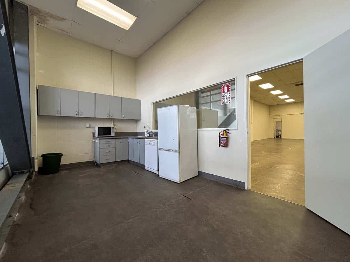 Modern office kitchen with white appliances and grey cabinets in a commercial space.